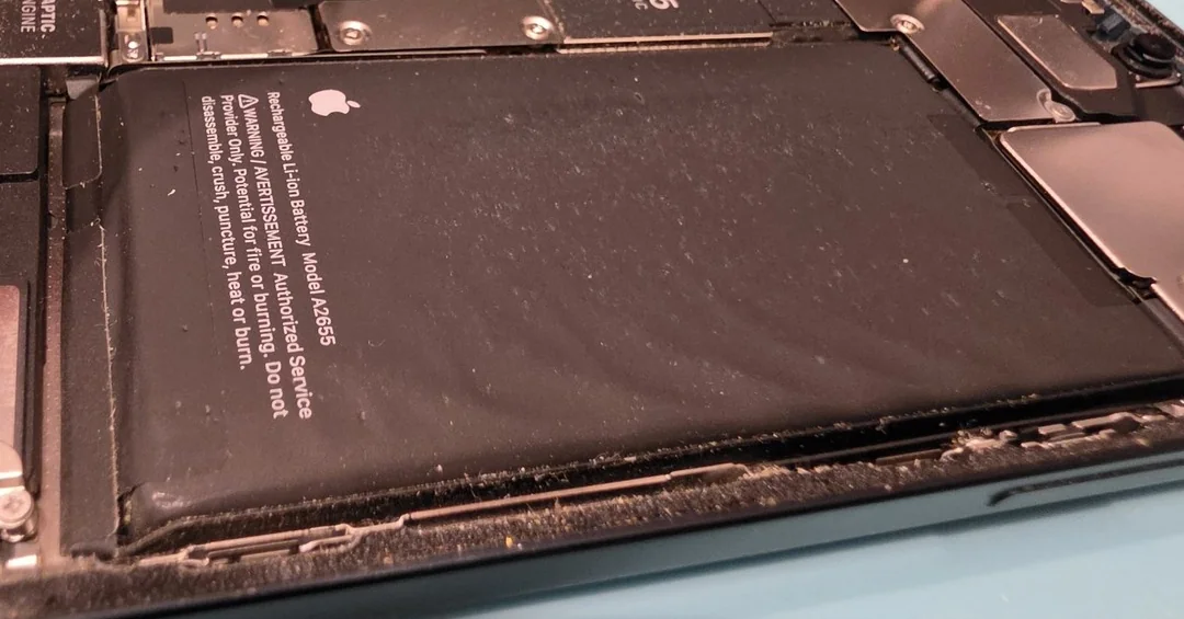 Swollen iPhone 13 battery bulging inside the opened phone on the bench, ready for a battery replacement in Coffs Harbour